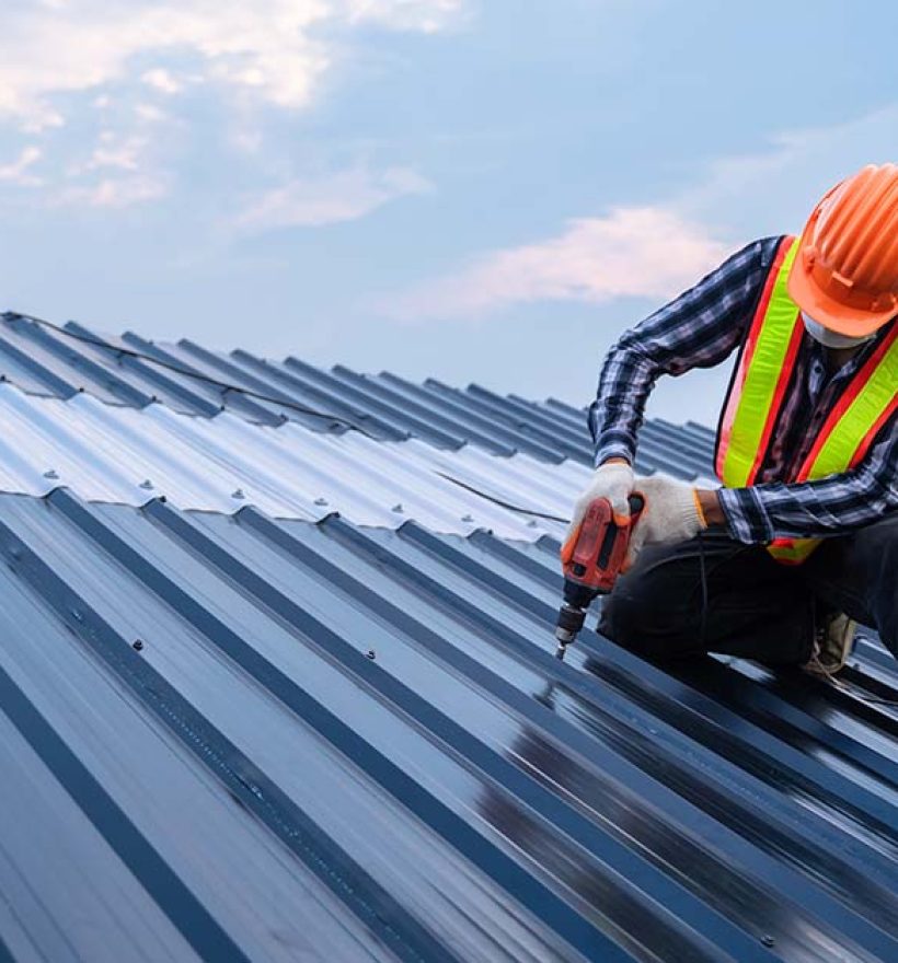 Asian Roofer worker safety wear using air or pneumatic nail gun and installing on new roof metal sheet, Roof concept of residential building under construction.